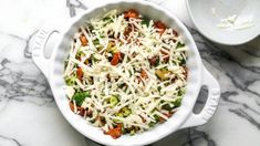 a casserole dish with cheese and vegetables in it on a marble counter top