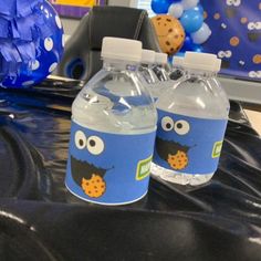 two water bottles sitting on top of a table with balloons and decorations in the background