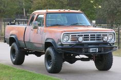 an orange pick up truck driving down a street