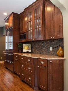 a kitchen with wooden cabinets and granite counter tops, along with hardwood flooring that matches the walls