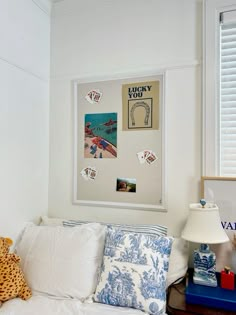 a white couch with blue pillows and pictures on the wall above it in a bedroom