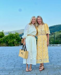 two women standing next to each other holding bags