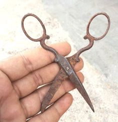 an old rusty pair of scissors held in someone's hand with no nails on it