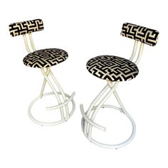 two stools with black and white designs on the back, one is shaped like a chair