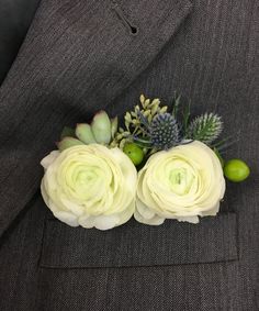 a boutonniere with white flowers and succulents on the lapel