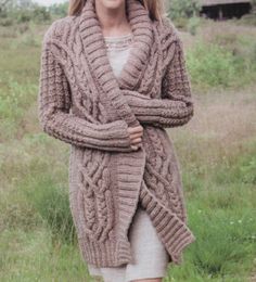 a woman standing in the grass wearing a cardigan