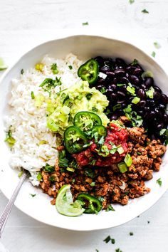 a white bowl filled with rice, beans and vegetables