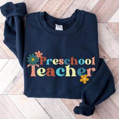 Welcome back the new school year with this very cute retro navy blue preschool teacher sweatshirt.  Embrace sweater weather and show up to class with this cozy and comfortable fall teacher sweater. This sweater is made from polyester and cotton. This combination helps designs come out looking fresh and beautiful.  The collar is ribbed knit, so it retains its shape even after washing.   Knit in one piece using tubular knit, it reduces fabric waste and makes the garment more attractive.  There are no itchy side seams on these sweaters.  .: 50% Cotton 50% Polyester .: Medium-heavy fabric 8.0 oz. .: Loose fit .: Sewn in label .: Runs true to size Care Instructions:  Machine wash: warm (max 40C or 105F); Non-chlorine: bleach as needed; Tumble dry: medium heat; Do not iron; Do not dryclean. Orde Blue Pre-shrunk Sweatshirt For Fall, Cute Cotton Sweatshirt For School, Cute Letter Print Sweatshirt For School, Blue Cotton Back To School Tops, Blue Cotton Top For Back To School, Blue Cotton Tops For Back To School, Blue Crew Neck Tops For Back To School, Retro Blue Tops For School, Blue Pre-shrunk School Spirit Sweatshirt