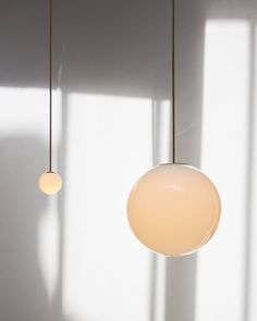 three lights hanging from the ceiling in a room with white walls and shadows on the wall