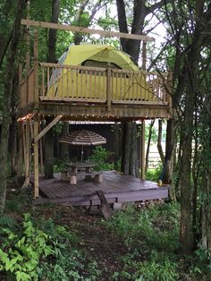 a wooden deck in the woods with an umbrella over it