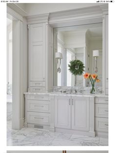 a white bathroom with two sinks and large mirrors on the wall next to each other