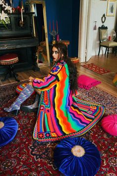 a woman sitting on top of a colorful rug