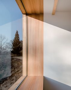 the window is looking out onto a field with trees in it and snow on the ground