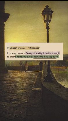 an old fashioned street light with a sign in the foreground that reads, in english we say kindness