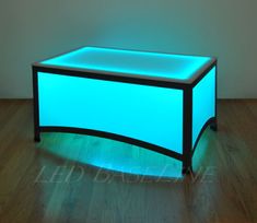 an illuminated coffee table in the middle of a room with wood floors and hard wood flooring