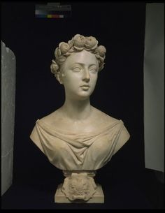 a statue of a woman with flowers in her hair is shown against a black background