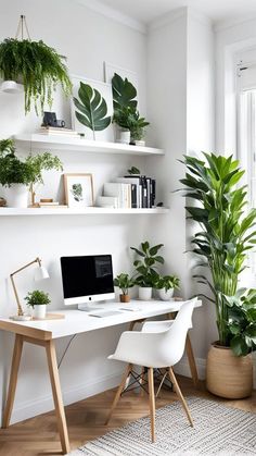 a white desk topped with a computer next to a plant