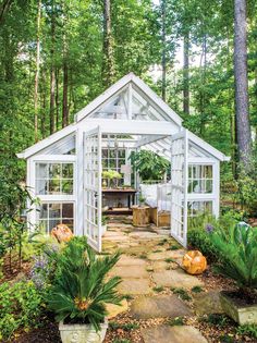 a white greenhouse in the middle of a forest