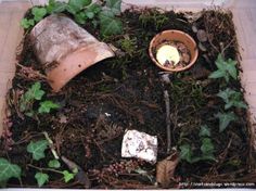 a planter filled with dirt and plants next to a potted plant on the ground