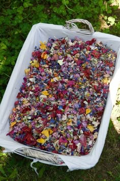 a large white container filled with lots of different colored flowers on top of green grass