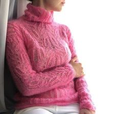 a woman wearing a pink sweater and white pants sitting in front of a window with her hands on her hips