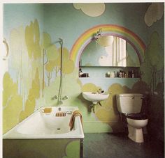 a bathroom with a rainbow painted on the wall next to a sink, toilet and mirror