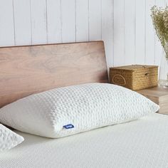 a close up of a pillow on a bed with a wooden headboard in the background