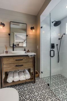 a bathroom with a sink, toilet and shower stall in the middle of it that has black and white tiles on the floor