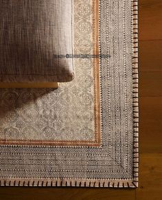 an area rug on the floor with a pillow next to it and a wooden table