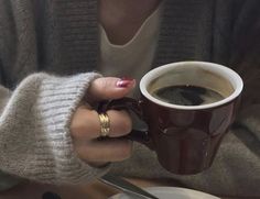 a woman holding a cup of coffee in her hands