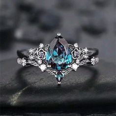 an image of a ring with blue and white stones on it, sitting on a black surface