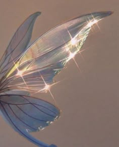 a blue butterfly flying through the air with its wings spread out and sparkling lights on it's back