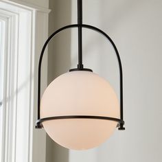 a light fixture hanging from the ceiling in a room with white walls and windows behind it