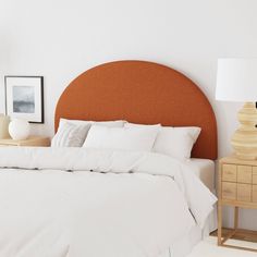 a bed with white linens and pillows in a small room next to a lamp