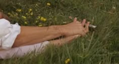 a woman laying in the grass with her hands on her face and hand extended out