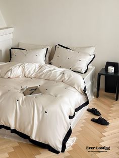 a bed with white sheets and black trims in a room next to a piano