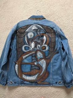 someone is holding up a jean jacket with an image on it