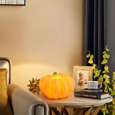 a small pumpkin sitting on top of a table next to a book and some pictures