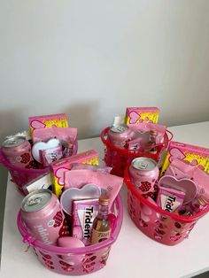 pink baskets filled with various items on top of a white table next to a wall