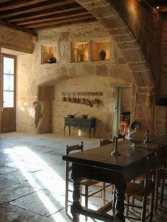 an old stone house with wooden tables and chairs in the room, along with other antique furniture