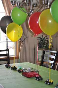 a table topped with lots of balloons and cars