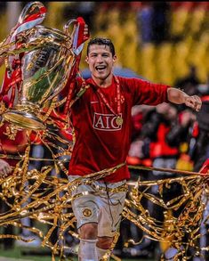 a soccer player is holding the trophy in his right hand and smiling at the camera