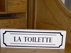 a sign that says la toilette sitting on top of a wooden table next to drawers