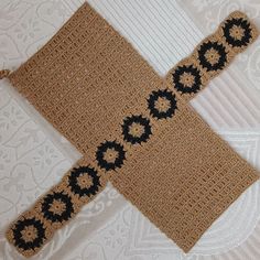 a crocheted object is laying on a white tablecloth with black and brown circles