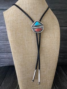 a necklace on a mannequin with a turquoise and red stone in the center