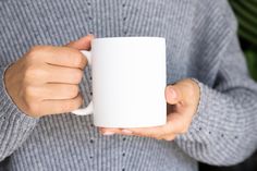 a person holding a white coffee mug in their hands