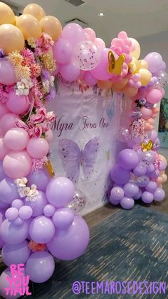 the balloon arch is decorated with flowers and butterflies