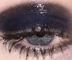 an eye with long lashes and glitters on the eyeshade is seen in this close up photo