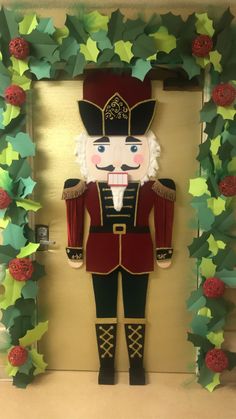 a nutcracker is standing in front of a christmas wreath with holly garlands