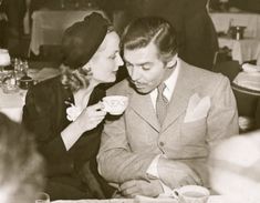 an old black and white photo of two people drinking tea together, the man is kissing the woman's face